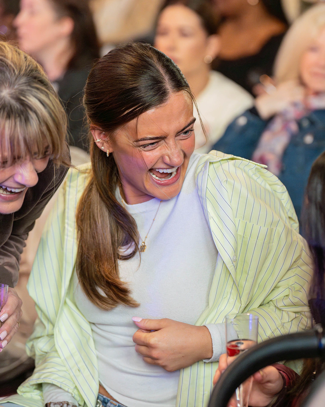 A woman laughing at a Rise gathering, in a pale green shirt